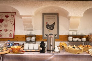 Un bufé de desayuno con diversas opciones de comida, una estación de café y una decoración en la pared con un gallo.