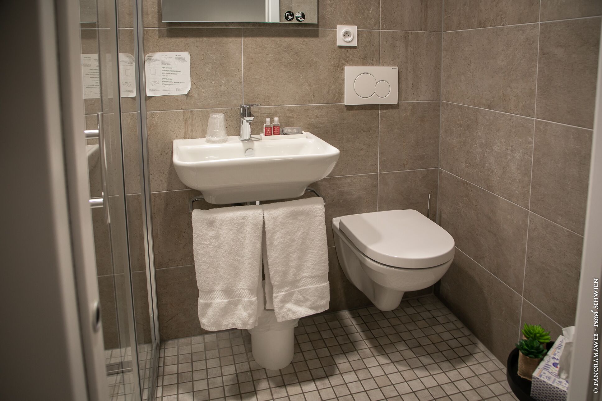 Un bagno con lavandino, WC e cabina doccia in vetro.