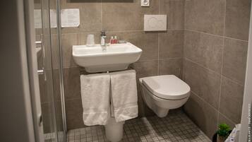 Un bagno con lavandino, WC e cabina doccia in vetro.