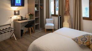 A hotel room with a bed, a desk with a chair, a television, and a wardrobe. - Hotel Restaurant Saint Nicolas (Riquewihr)