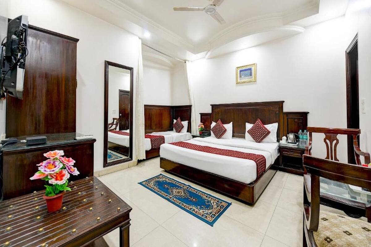 A hotel room with a large bed, two bedside tables, a ceiling fan, a mirror, and a wooden dresser.