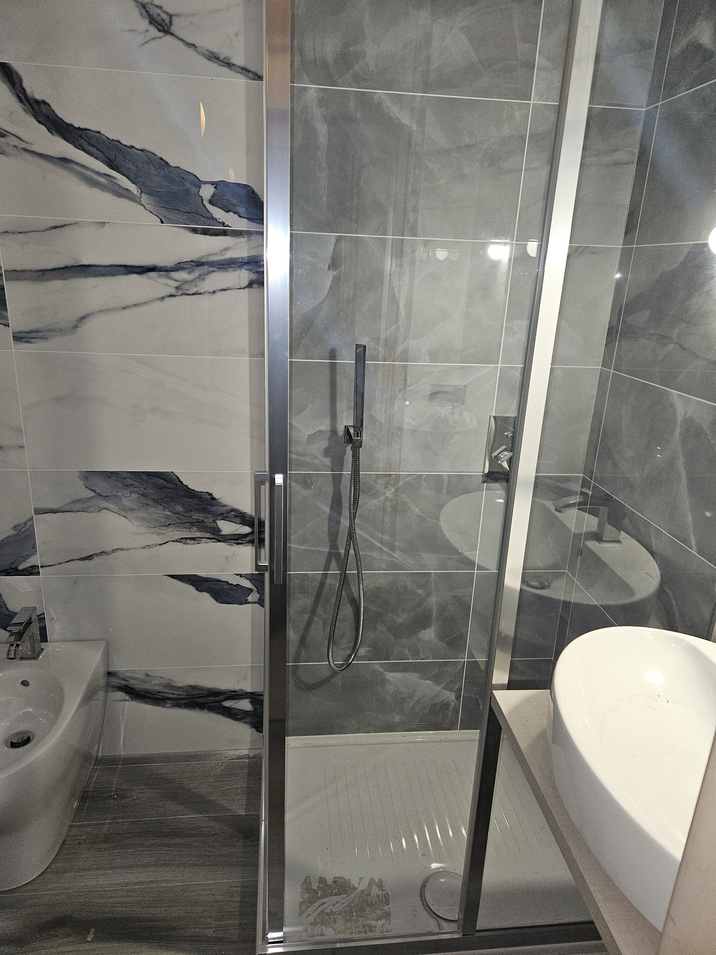 Une salle de bain moderne avec une douche à parois de verre, une baignoire blanche et un bidet.