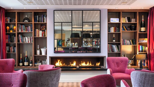 Un salon moderne doté d’une cheminée, de bibliothèques et de sièges confortables.