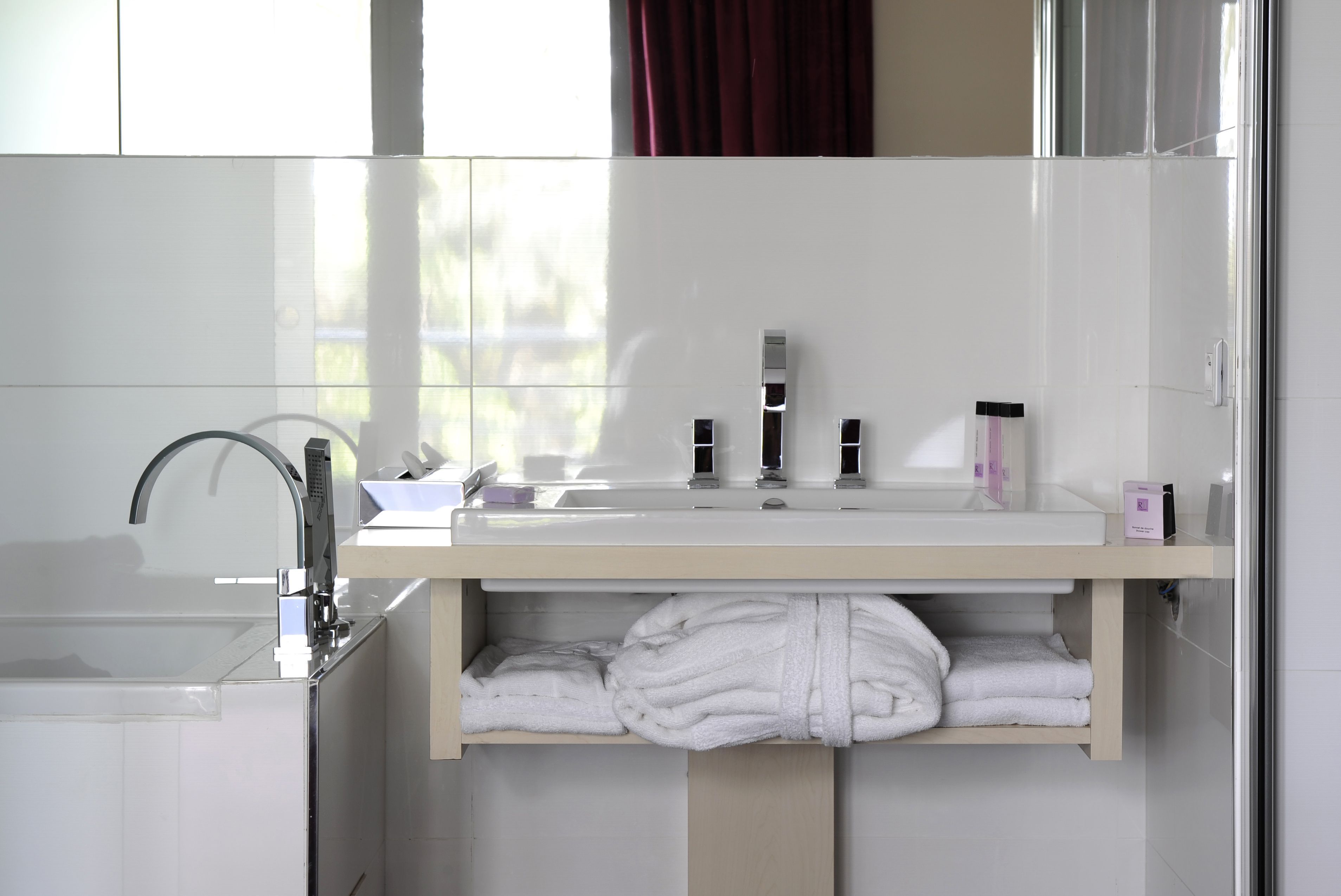 Un baño moderno con un espejo grande, un lavamanos y un perchero para toallas.