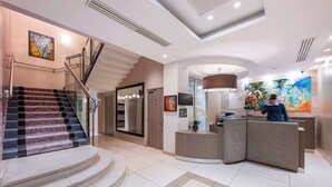 Un hall d’hôtel moderne avec un escalier, un comptoir d’accueil et des œuvres d’art.