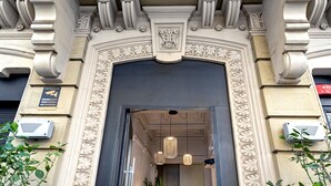 Una entrada ornamentada con un arco oscuro, molduras decorativas y un cartel que indica zona de videovigilancia.