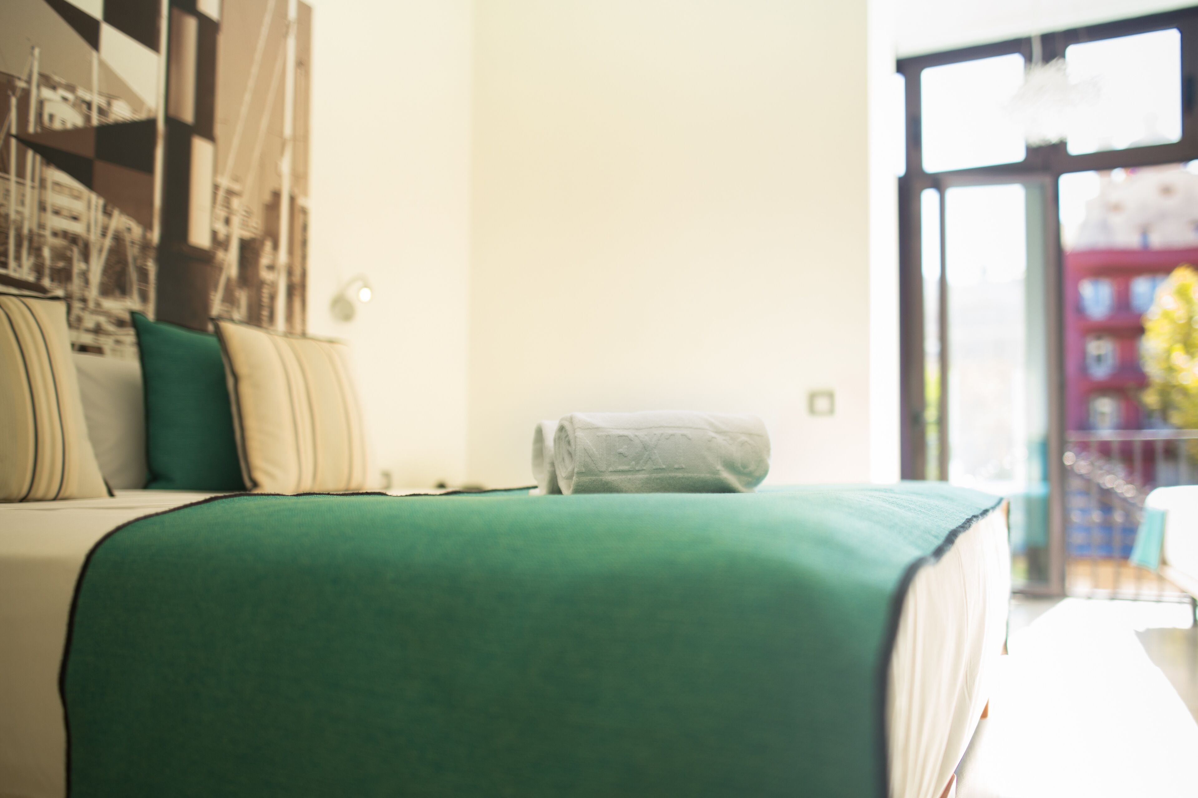 Un dormitorio con cama, almohadas, ventana y vistas al exterior.