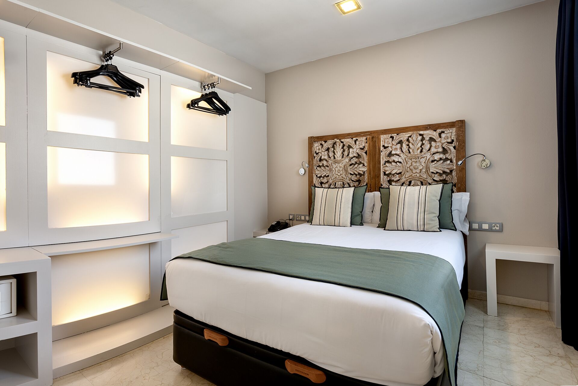 Un dormitorio con cama, armario con espacio para colgar, mesita de noche y cabecero decorativo.