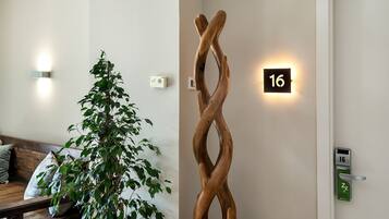 Un interior moderno con una escultura de madera, una planta y un cartel con el número 16.