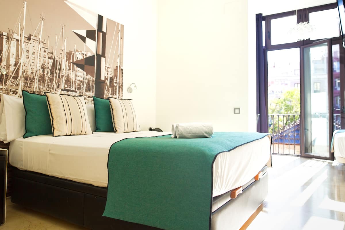 A hotel room with a bed, a nightstand, a large window, and a view of the outside.