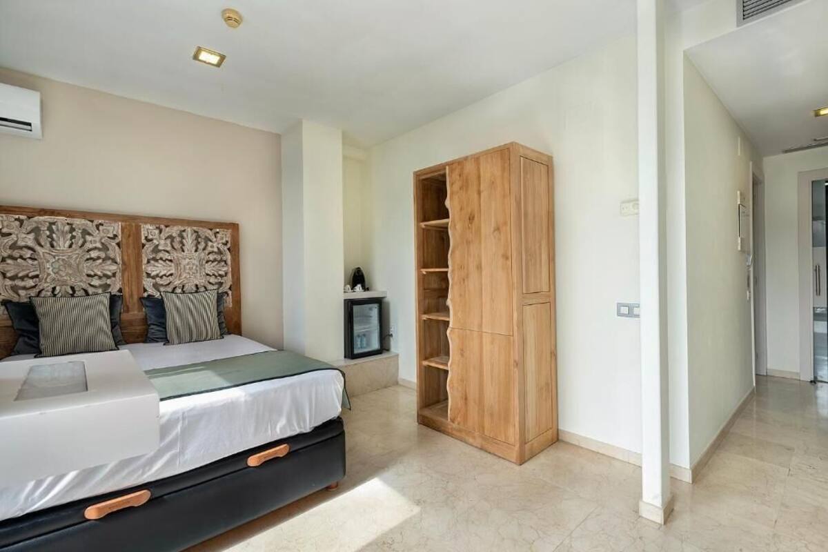A bedroom with a bed, a wooden wardrobe, and a small TV.