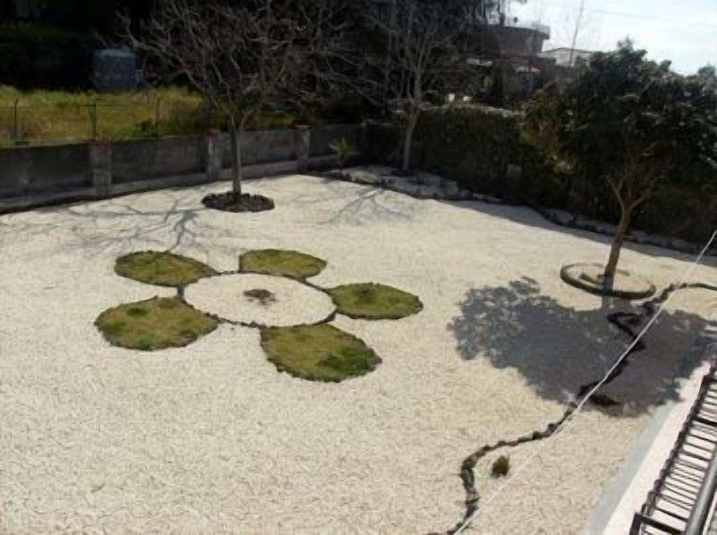 A rooftop garden with a circular flower design, trees, and a railing.