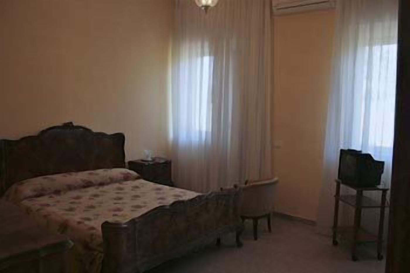 Un dormitorio con una cama, una mesita de noche, una silla y un televisor.