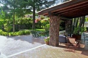 An outdoor patio area with stone flooring, a pergola structure, and outdoor furniture. - Rosso Vulcano Bed & Breakfast (Nicolosi)