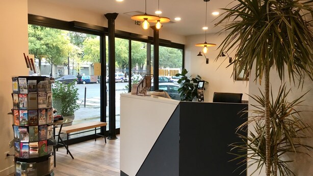 Un área de recepción con piso de madera, un mostrador negro y una planta.