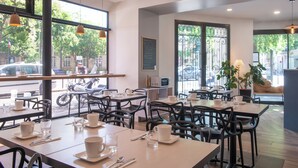 Un café con mesas y sillas, un menú en la pizarra y grandes ventanales con vista a la calle.