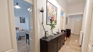 A hallway with a dark wooden console table, a framed abstract painting, and a vase with red roses. - Santi Quattro al Colosseo (Rome)