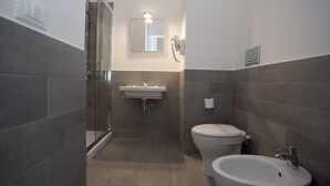 A modern bathroom with a glass shower enclosure, a sink, a toilet, and a bidet. - Santi Quattro al Colosseo (Rome)