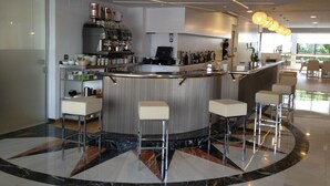 Zona de bar moderna con una barra curva, taburetes y una máquina de café.