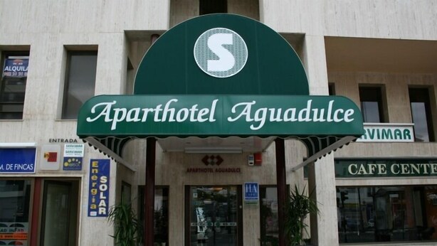 The entrance to Aparthotel Aquadulce with a prominent sign, a cafe center, and a solar energy sign. - Aguadulce (Roquetas de Mar)