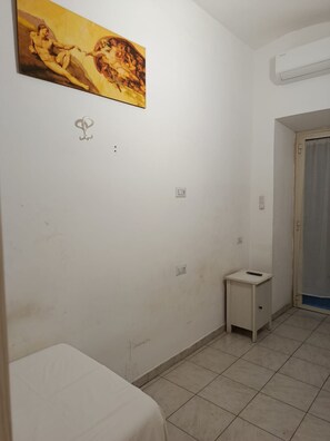 A room with a bed, a small bedside table, a painting on the wall, and a door leading to another room. - Prince Inn (Rome)