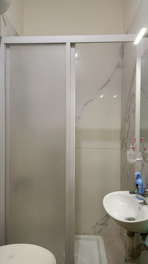 Casa de banho com uma pia branca, um espelho e cabine de duche.