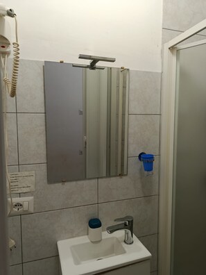 A bathroom with a mirror, a sink, and a shower. - Prince Inn (Rome)
