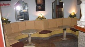 A seating area with cushioned benches and round tables, a mirror, and wall-mounted lights. - Villa Angela (Split)