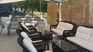 An outdoor patio area with wicker furniture and tables, shaded by a canopy. - Villa Angela (Split)