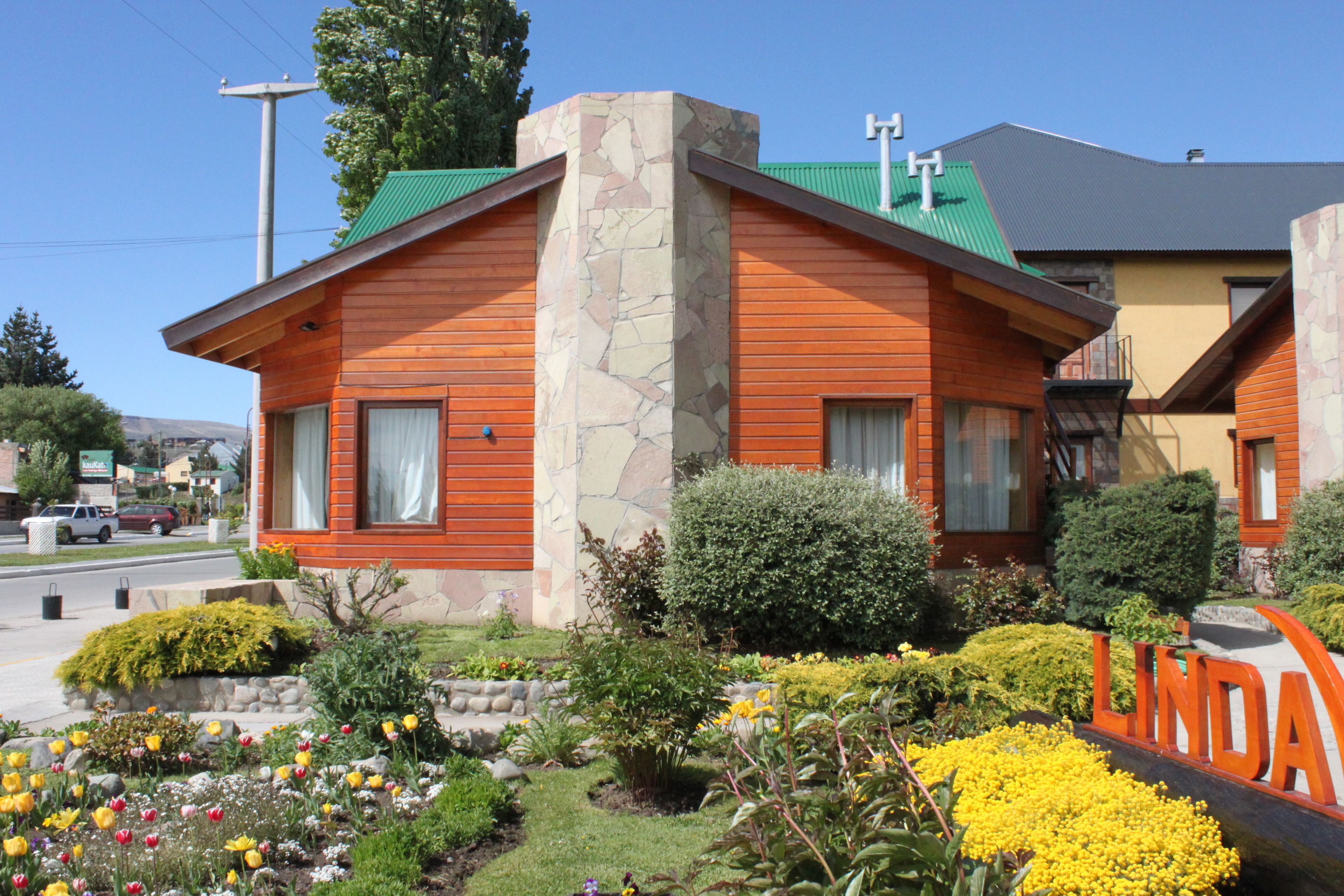 A two-story building with a stone facade and wooden siding, surrounded by a well-maintained garden with various flowers and shrubs.
