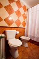 Un baño con dos inodoros, un lavabo y una cortina de ducha.