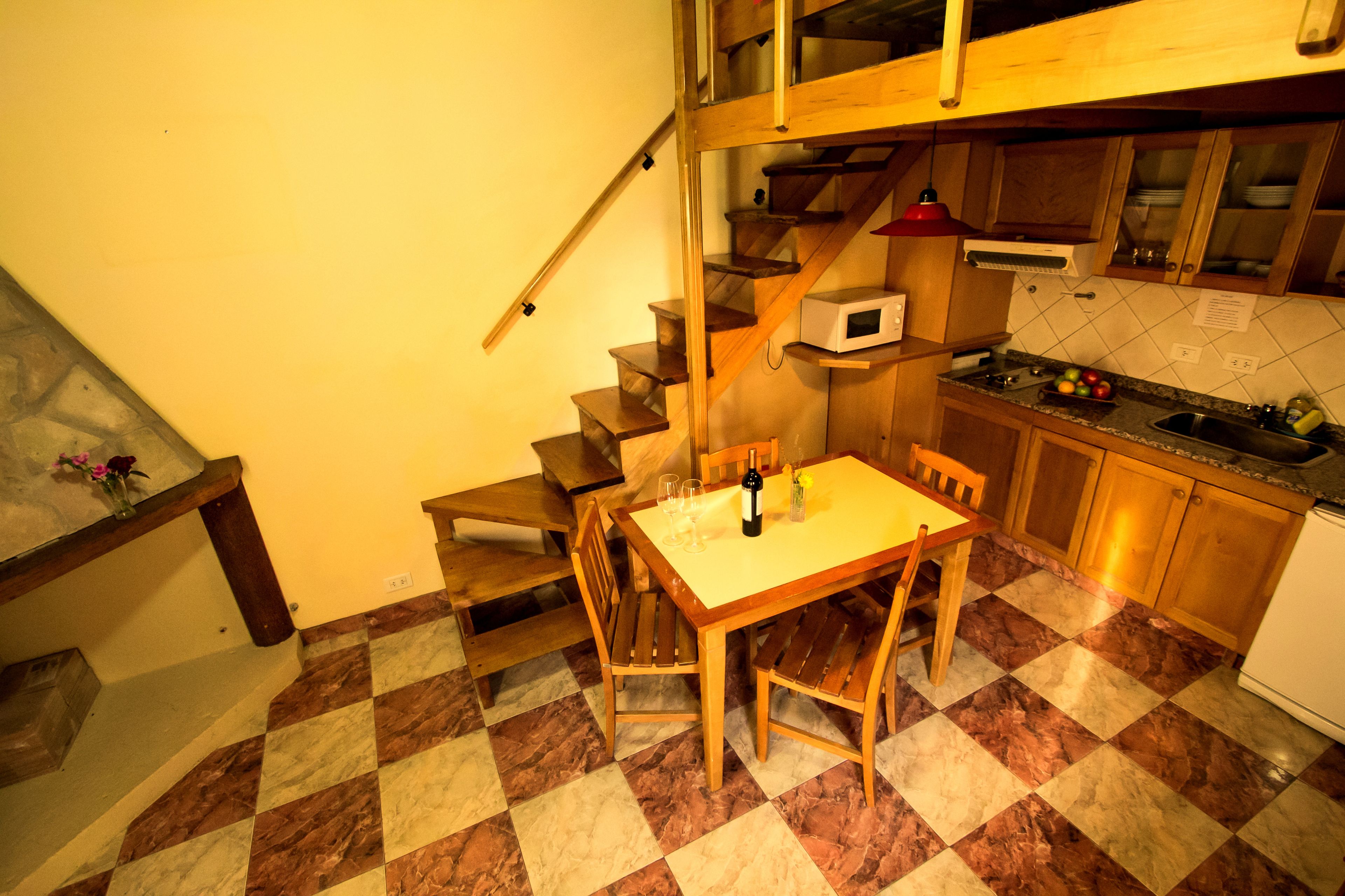 A kitchen with a wooden table and chairs, a microwave, and a sink.