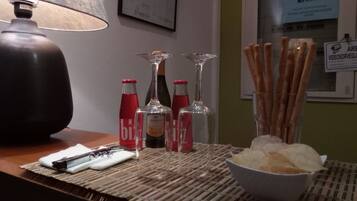 Un tavolo con una lampada, bottiglie, bicchieri e qualche snack.