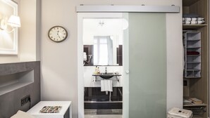 A modern hotel room with a bed, a bedside table, a nightstand, a bathroom with a sink and mirror, and a closet with shelves. - Ainb B&B Eixample Muntaner (Barcelona)