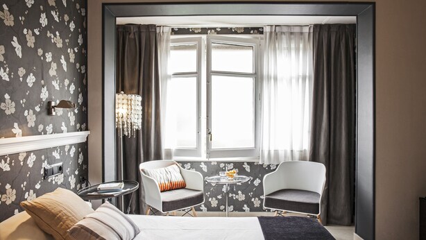 A hotel room with a bed, two armchairs, a small table, and a window with curtains. - Ainb B&B Eixample Muntaner (Barcelona)
