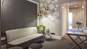 A modern living room with a sofa, ottoman, and a dining table with a vase of flowers. - Ainb B&B Eixample Muntaner (Barcelona)