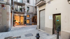 A narrow street with a shop on the left and a building entrance on the right.