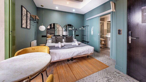 A modern bedroom with a bed, bedside tables, a vanity, and a mirror.