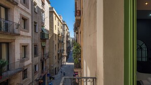 A narrow street between buildings with balconies, a visible door, and a window with a curtain.
