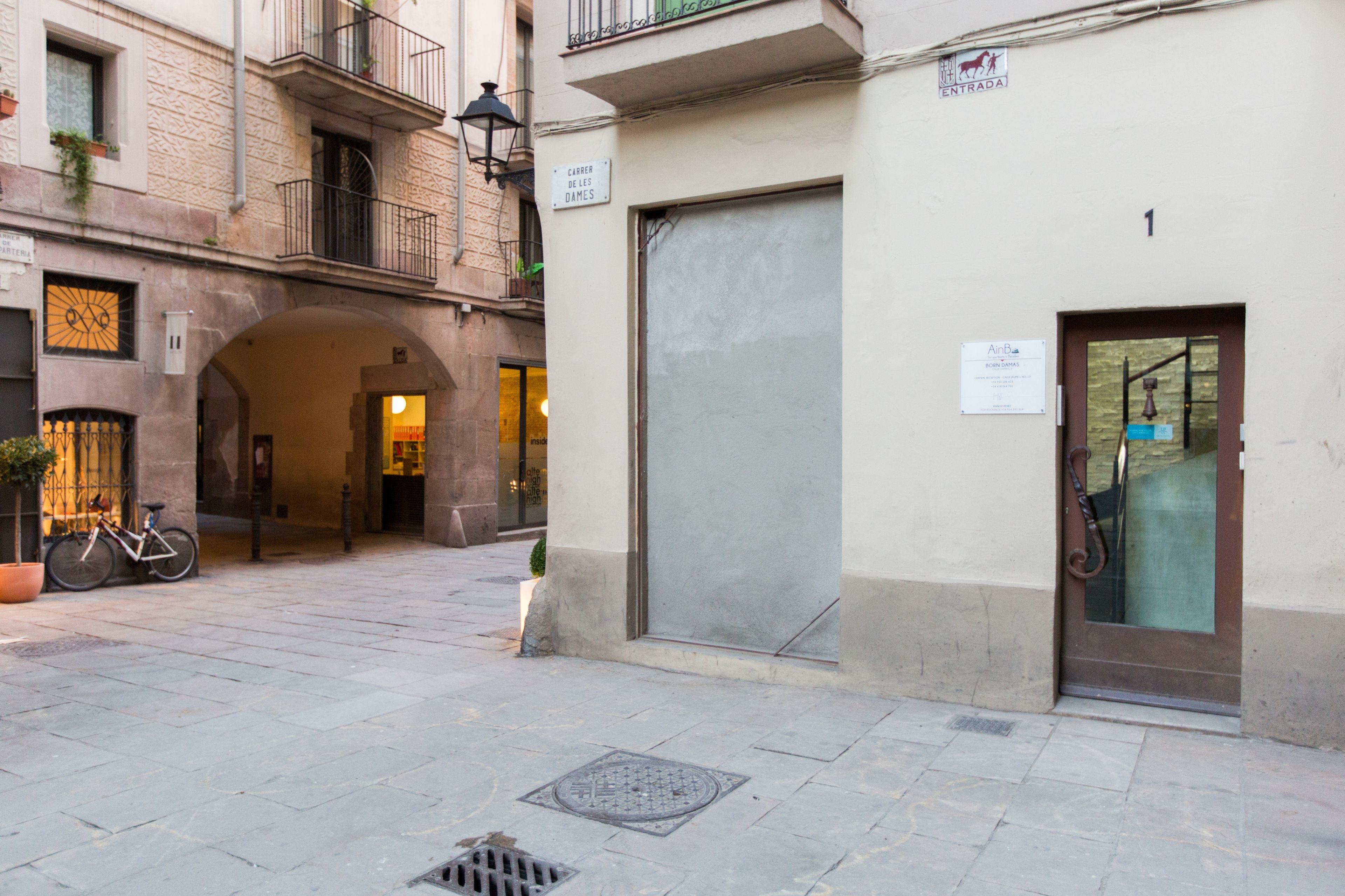 A narrow street with a closed shop door, a bicycle, and a manhole cover.