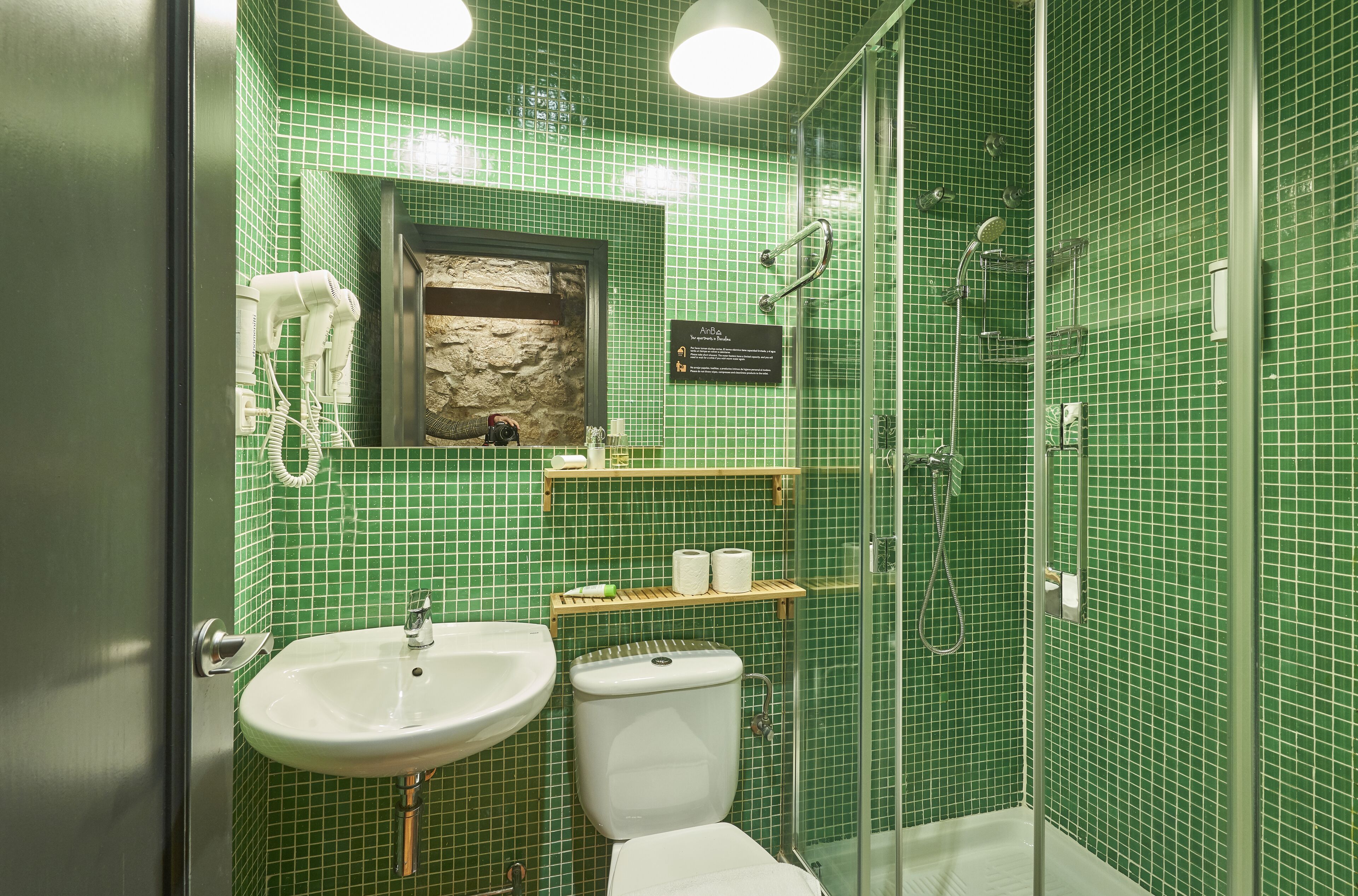 Een badkamer met groene tegels, een wastafel, toilet en een douchehoek.