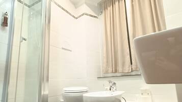 Un baño moderno con ducha envuelta en vidrio, inodoro, lavamanos y espejo.