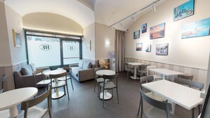 A hotel lobby with seating areas, a water dispenser, and artwork on the walls. - Hotel Helvetia (Genoa)