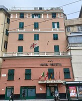 A multi-story hotel with a red facade, green shutters, and a flag. The sign reads "HOTEL HELVETIA."