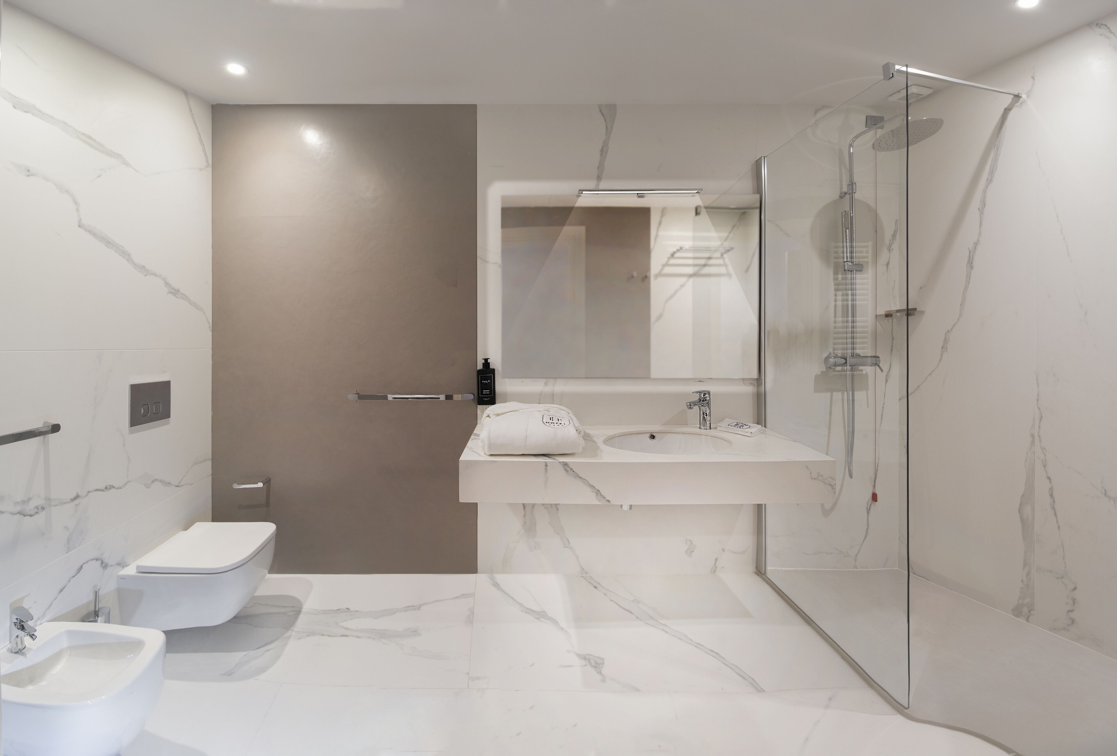 A modern bathroom with a toilet, bidet, and a glass-enclosed shower.