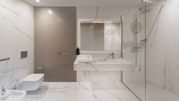 A modern bathroom with a toilet, bidet, and a glass-enclosed shower.
