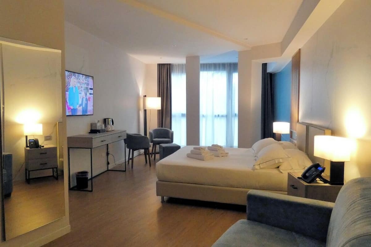 Une chambre d’hôtel avec un lit, un bureau, une chaise, une télévision et une lampe.