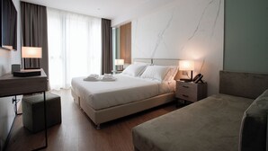 Una habitación de hotel moderna con una cama grande, mesitas de noche, un escritorio y una silla.