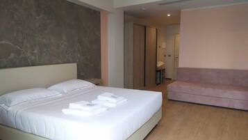 Una habitación de hotel moderna con una cama grande, un sofá rosa y una pared de acento de mármol.