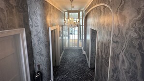 Un pasillo con paredes de diseño de mármol, un candelabro y una puerta que da a una habitación.